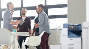 5 people standing around a table next to a photocopier