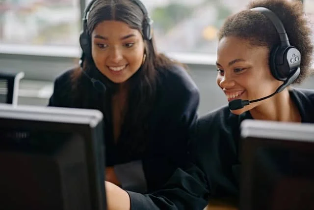 support team two people looking at a computer screen and smiling